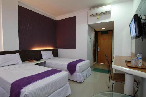 a hotel room with two beds and a television at YUTAKA INN Kalimas Ampel Surabaya in Surabaya