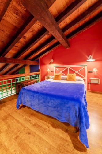 a bedroom with a blue bed in a red wall at Apartamentos Rurales & Spa La Bárcena in Enterria