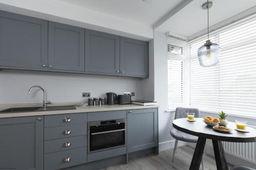 a kitchen with gray cabinets and a small table with a table at Bell House Oxford - The Punt in Oxford