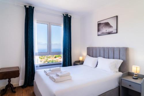 a bedroom with a bed with a large window at GuestReady - Caniço city view in Caniço