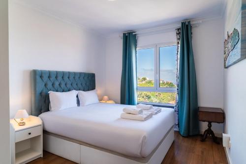 a bedroom with a bed with a blue headboard and a window at GuestReady - Caniço city view in Caniço