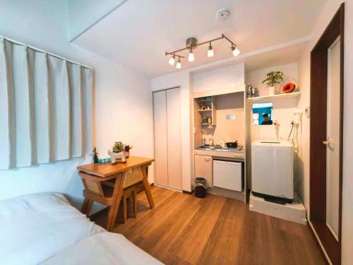 a bedroom with a bed and a desk and a kitchen at Mossy Nest Negishi I 鶯谷駅徒歩7分 上野徒歩圏内 in Tokyo