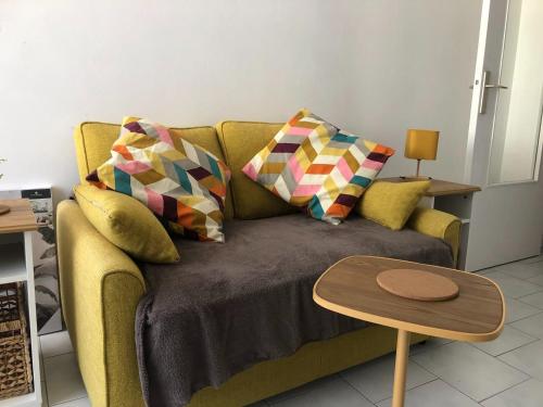 a living room with a couch with pillows and a table at Grand Studio calme centre-ville in La Ferté-sous-Jouarre