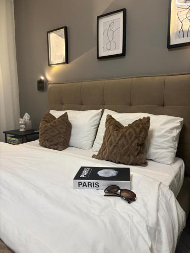 a large white bed with a book on it at Luxury 3 Bed Apartment with Large Outdoor Pools and Gardens in Qala