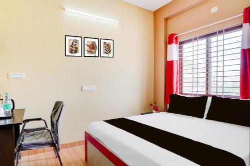 a bedroom with a bed and a desk and a window at Hotel O PALMS INN ELEGANT STAY in Bengaluru