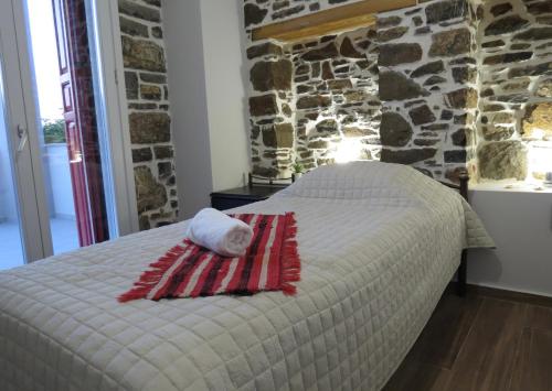 a bed in a room with a stone wall at Rodonas-Apartments in Volissos
