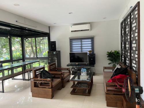 a living room with wooden furniture and a tv at Thanh Xuân Ecolodge in Ðào Lãng