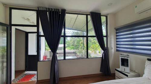 a bedroom with a large window with black curtains at Thanh Xuân Ecolodge in Ðào Lãng