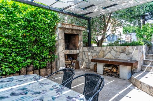 a patio with a table and a stone fireplace at Apartments Nina in Maslenica