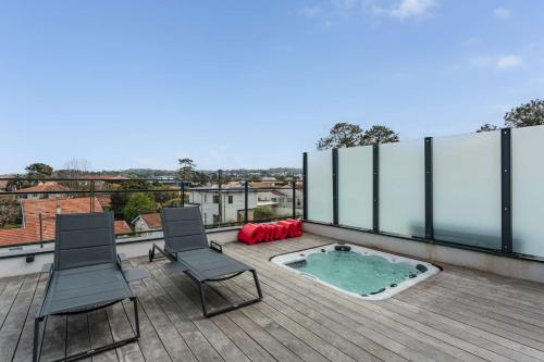 un patio avec deux chaises et un bain à remous sur le toit dans l'établissement Rooftop avec jacuzzi et vue dégagée haut de gamme, à Anglet