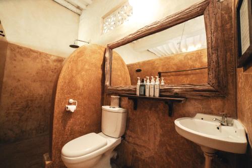 a bathroom with a toilet and a sink and a mirror at Banana House and Wellness Centre in Lamu
