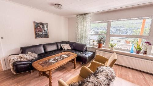 a living room with a leather couch and a table at VILLA ORANGE - Spacious piano home in Klaksvik in Klaksvík