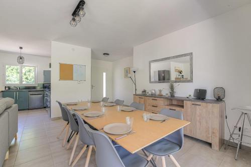 a dining room with a table and chairs and a kitchen at Charmante maison 6 à 8 pers PMR proche Lyon in Seyssuel