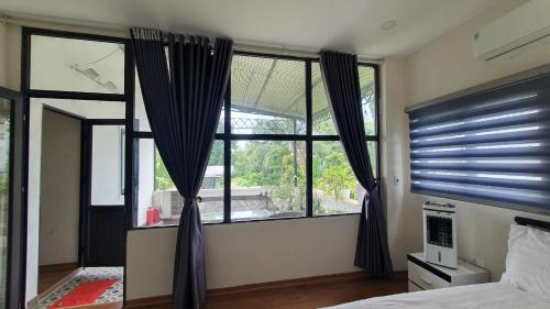 a bedroom with a bed and a large window at Thanh Xuân Ecolodge in Ðào Lãng