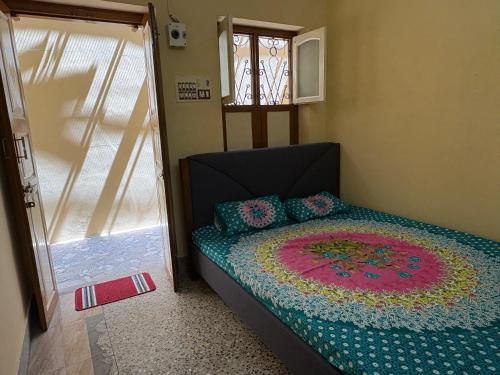 a bedroom with a bed with a colorful quilt on it at Divine Homestay in Tiruvannāmalai