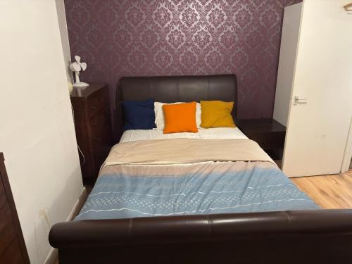 a bed with orange and blue pillows in a bedroom at Pdmdecor House in Hunslet