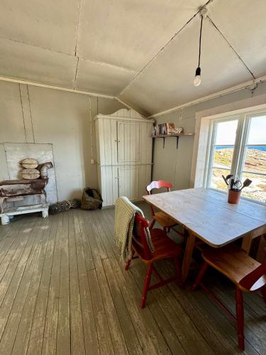 a dining room with a wooden table and chairs at Fiskeværet Nesland in Kvalvik
