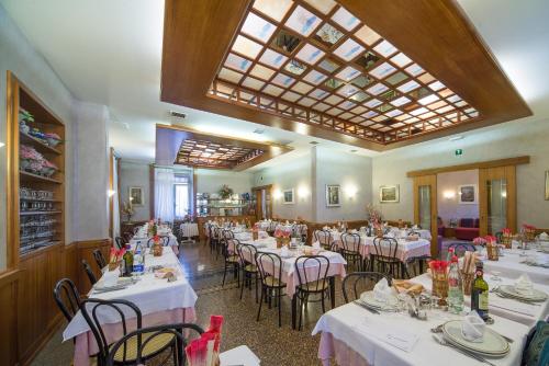 comedor con mesas y sillas blancas y techo en Miramonti, en Calizzano