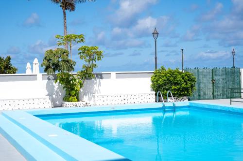 a swimming pool with blue water and a fence at Waves Views in Punta del Hidalgo