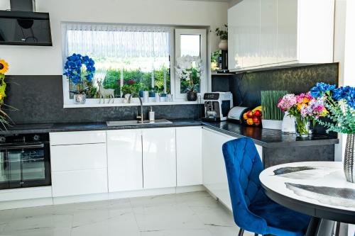 a kitchen with white cabinets and a table with blue chairs at Dom w Karkonoszach 2 in Podgórzyn