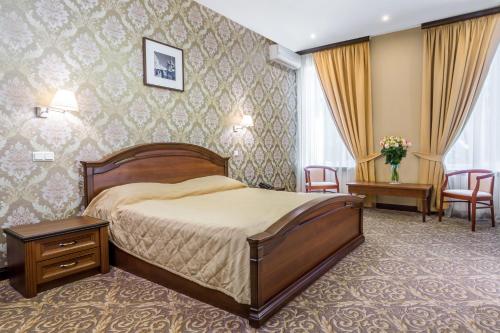 ein Hotelzimmer mit einem Bett und zwei Stühlen in der Unterkunft M-Hotel in Sankt Petersburg
