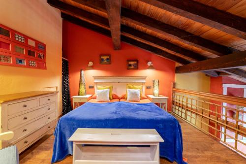 a bedroom with a blue bed and red walls at Apartamentos Rurales & Spa La Bárcena in Enterria