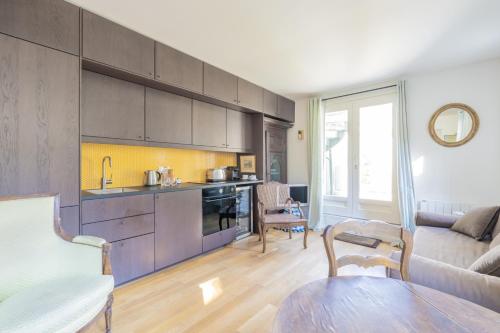 une cuisine et un salon avec un canapé et une table dans l'établissement Coeur de Versailles - Vue jardin apaisante & calme, à Versailles