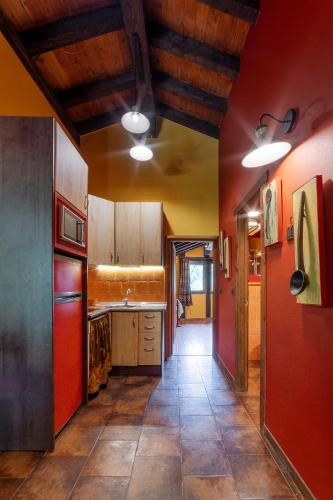 a kitchen with red walls and wooden ceilings at Apartamentos Rurales & Spa La Bárcena in Enterria
