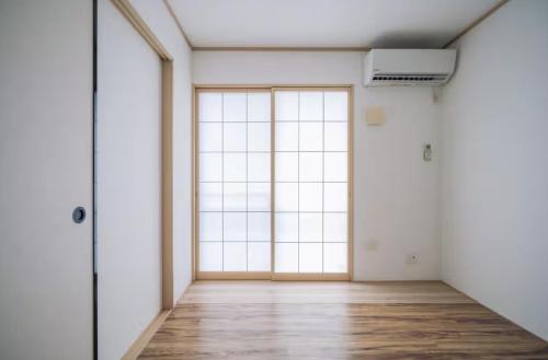 an empty room with large windows and wooden floors at Comfort Miyabi -4号棟 in Yomitan