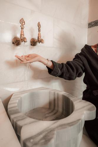 a woman is reaching for a metal bowl on a wall at The Local House Alaçatı in Alacati