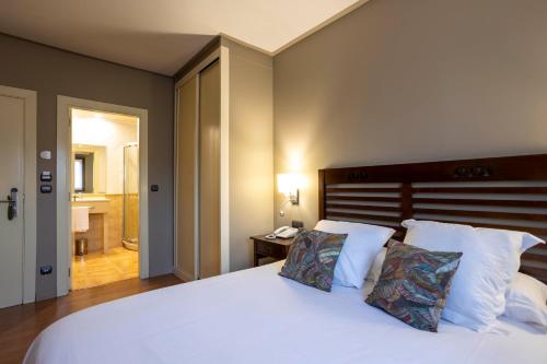 a bedroom with a large white bed and a bathroom at Hotel Spa Gametxo in Ibarrangelu