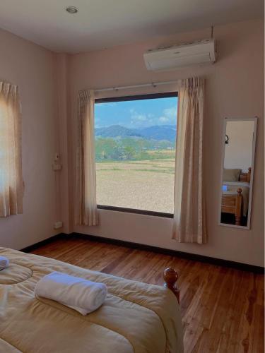 a bedroom with a large window with a view at Chomdoi Villa in Ban Samai (2)