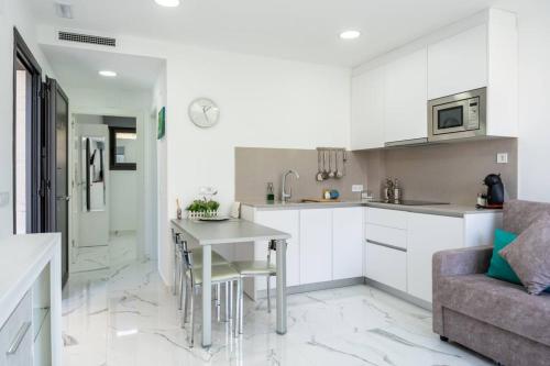 a kitchen and living room with a table and a couch at Apartamentos Rosa de Abril in Teià