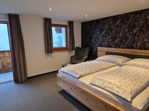 a bedroom with a large bed and a chair at Ferienhaus Lerch in Sankt Gallenkirch