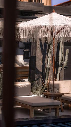a patio with an umbrella and a table and benches at The Local House Alaçatı in Alacati