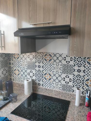 a kitchen with a tiled wall with a stove at Saidia in Saidia 