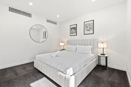 a white bedroom with a white bed and a mirror at Big Two-Story with Private Elevator & Balconies in Sydney
