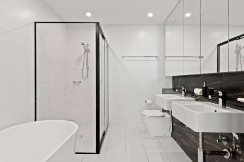 a white bathroom with two sinks and a shower at Big Two-Story with Private Elevator & Balconies in Sydney