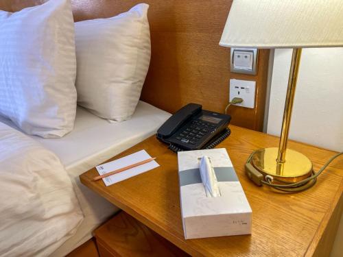 a bed with a phone and a lamp on a table at Aqaba Gulf Hotel By FHM in Aqaba