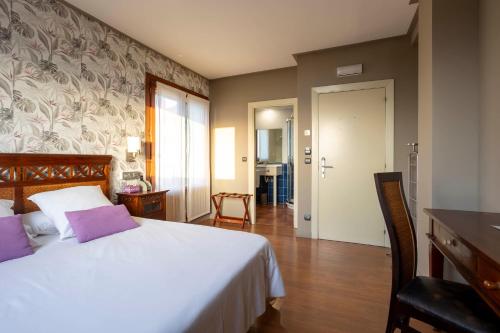 a bedroom with a large white bed with purple pillows at Hotel Spa Gametxo in Ibarrangelu