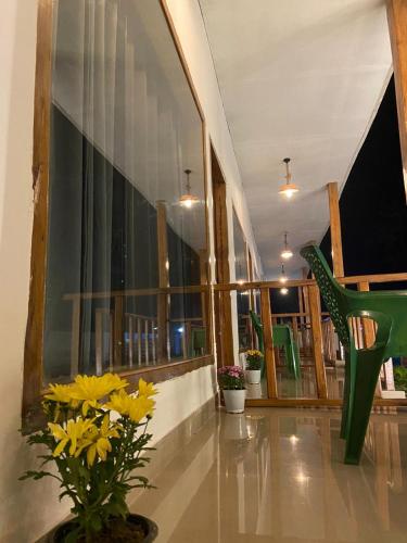 a lobby with a green chair and yellow flowers at Wildscape kaziranga in Kāziranga