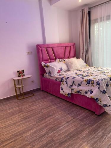 a bedroom with a pink bed with a purple headboard at Maison Royale in Kofa