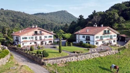 two houses on a hill next to a road at Hotel Spa Gametxo in Ibarrangelu