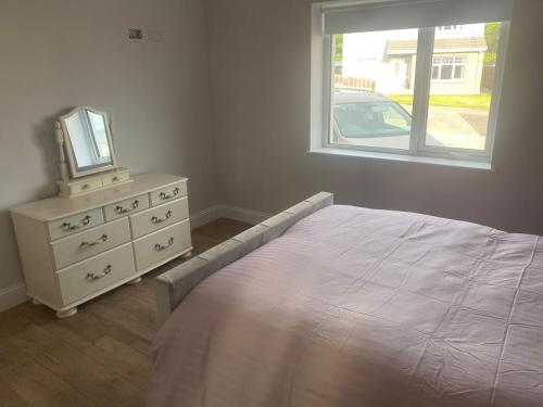 a bedroom with a bed and a dresser and a window at Spacious 5 bedroom house in Buncrana in Buncrana