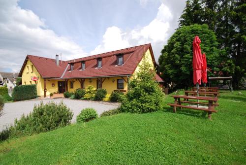 una casa con una mesa de picnic y una sombrilla roja en Penzion Lipno Jantar en Horní Planá