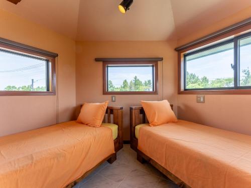 two beds in a room with two windows at Tabist Elias Garden in Ichinomiya