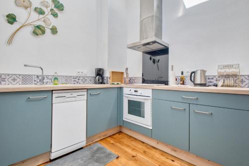 une cuisine avec des armoires bleues et des appareils blancs dans l'établissement Appartement 4 pers, climatisé, à Eymet