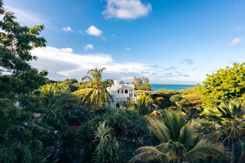 a white house in the midst of trees and plants at Banana House and Wellness Centre in Lamu