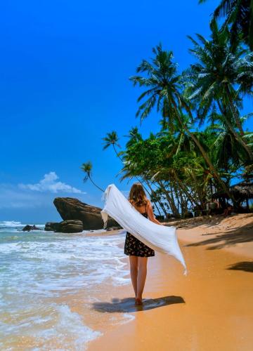 a young girl walking on the beach with a towel at Oceanview in Talpe
