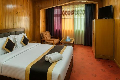a hotel room with a large bed and a chair at Hotel New Broadway in Patnitop